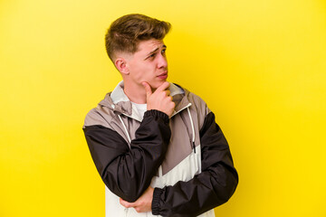 Fototapeta premium Young caucasian man isolated on yellow background thinking and looking up, being reflective, contemplating, having a fantasy.