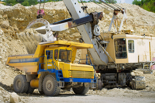 An excavator loads a huge truck with rock.