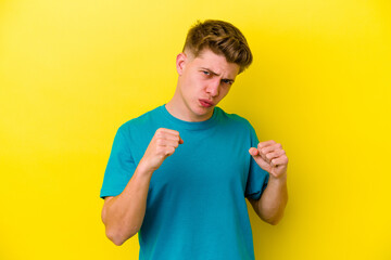 Young caucasian man isolated on yellow background showing fist to camera, aggressive facial...