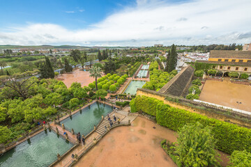 Naklejka premium Cordoba, Andalusia, Spain - April 20, 2016: tourists walking along the popular gardens of Alcazar de los Reyes Cristianos. Aerial view and skyline of Cordoba city.