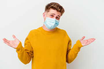 Young man wearing a mask for coronavirus isolated on white background doubting and shrugging shoulders in questioning gesture.