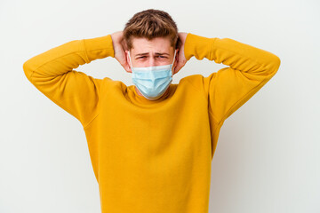 Young man wearing a mask for coronavirus isolated on white background covering ears with hands...