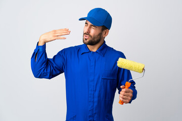 Painter man holding a paint roller isolated on white background with tired and sick expression