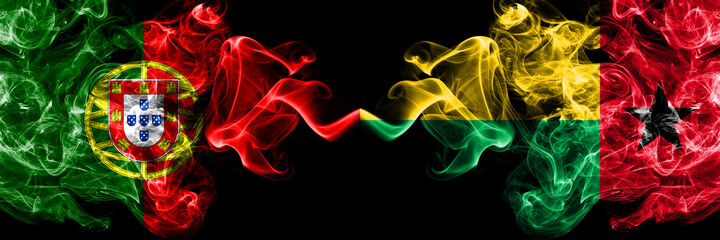 Obraz premium Portugal, Portuguese vs Guinea Bissau smoky mystic flags placed side by side. Thick colored silky abstract smoke flags.