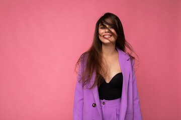 Fototapeta premium Portrait of positive delightful beautiful fashionable brunette woman in casual trendy violet jacket isolated on pink background with free space