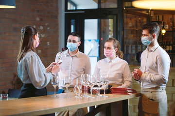 The waiters of the restaurant in a medical mask learns to distinguish between the glasses.