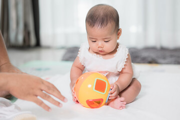Asian baby cute in the living room at home playing ball toy with family.
