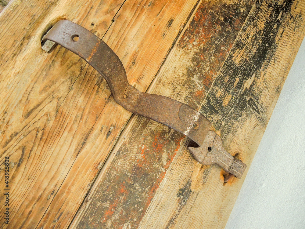 Poster closeup view of the old rusty metallic handle on a wooden piece