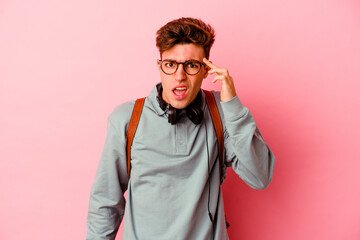 Young student man isolated on pink background showing a disappointment gesture with forefinger.