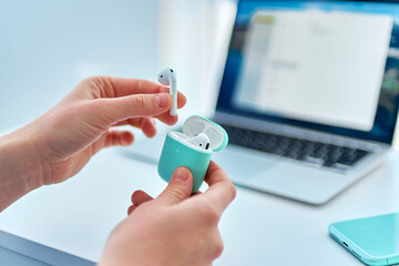 Using white modern wireless headphones while smart working at a computer