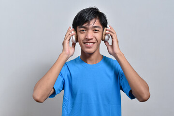 Happy young Asian boy teenager listening to music with his headphones