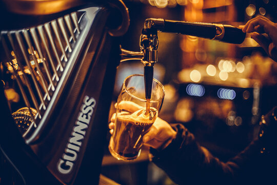 Bartender pouring a pint of Guinness beer in a pub
