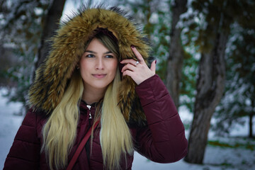 Beautiful blonde girl walking in the park on snowy winters day.