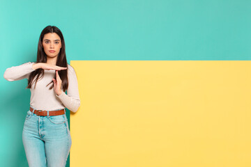young pretty woman looking serious, stern, angry and displeased, making time out sign. copy space...