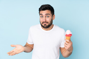 Caucasian man with a cornet ice cream isolated on blue background making doubts gesture while lifting the shoulders