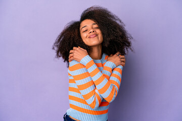 Young african american curly woman isolated on purple background hugs, smiling carefree and happy.