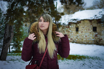Beautiful blonde girl walking in the park on snowy winters day.