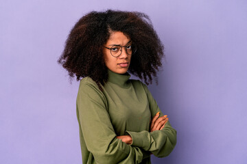 Young african american curly woman isolated on purple background suspicious, uncertain, examining you.