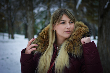 Beautiful blonde girl walking in the park on snowy winters day.