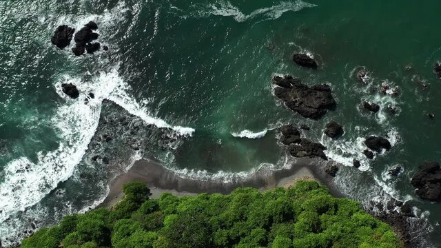 Top aerial shot of waves crashing on reefs Jaco coast Costa Rica