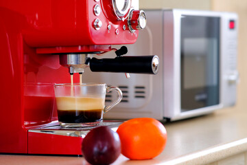 Two streams of espresso coffee on the espresso machine are poured into a transparent cup. Aromatic coffee with an appetizing foam.