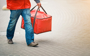Adult man delivering pizza and other fast food. Food delivery worker with red thermal backpack. Courier delivery pizza to homes and offices. Delivering online orders to customers from restaurants