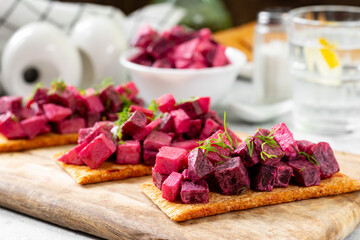 Bruschetta with pickled beetroot, apple and mayonnaise. Sandwich or crostini on a serving wooden board on a light gray table. Bruschetta with traditional Scandinavian beetroot and apple salad