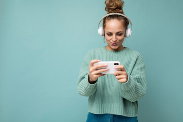 Attractive concentrated positive young woman wearing blue sweater isolated over blue background...