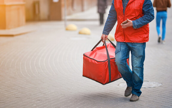 Food delivery worker with red thermal backpack. Adult man delivering pizza and other fast food. Courier delivery pizza to homes and offices. Delivering online orders to customers from restaurants
