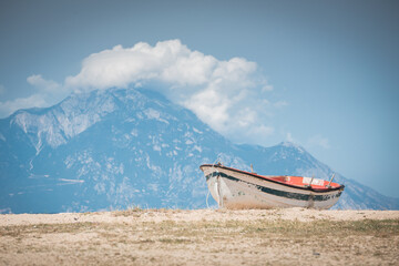 Small fishing boat on the shore with beautiful scenery - obrazy, fototapety, plakaty