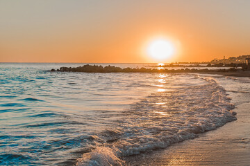 Obraz premium Orange sunset on the sea coast with small waves