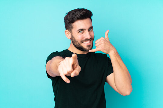 Caucasian handsome man isolated on blue background making phone gesture and pointing front