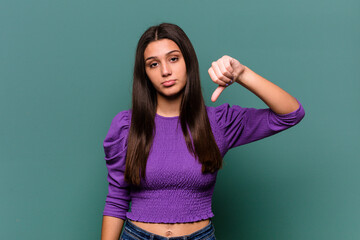 Young Indian woman isolated on blue background showing a dislike gesture, thumbs down. Disagreement...