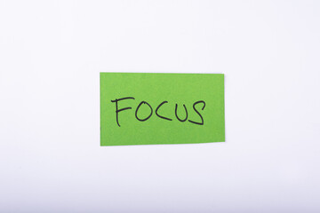 Focus word written on a Green color sticky note with a White background