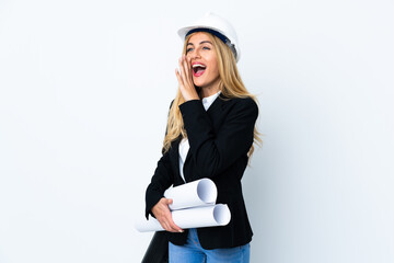Young architect woman with helmet and holding blueprints over isolated white background shouting with mouth wide open