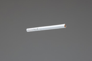 Single white unlit cigarette close up macro studio shot isolated on gray background shallow depth of field