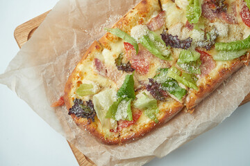Freshly baked pizza margherita with iceberg lettuce, parmesan, crackers and chicken on a wooden tray on a gray background. Italian Cuisine