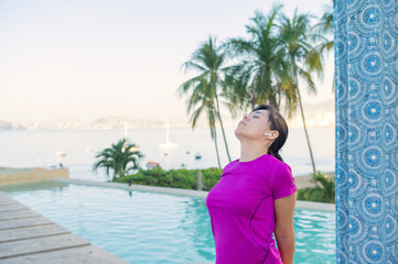 Woman practices yoga in front of the pool. Yoga poses outdoors in front of the sea. Yoga outdoors. Girl doing morning exercise in front of the pool in the pacific ocean. Healthy life concept.
