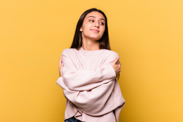 Obraz premium Young Indian woman isolated on yellow background hugs, smiling carefree and happy.