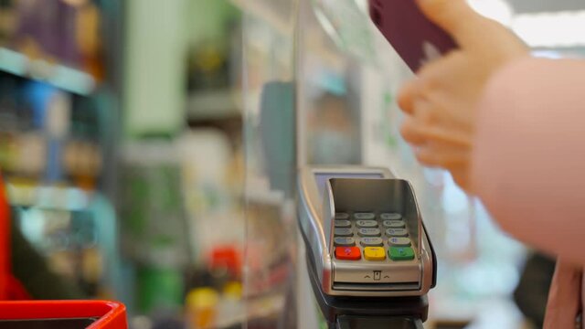 Mobile payment. Contactless payment with your smartphone. Wireless payment concept. Close-up, woman using smartphone cashless wallet NFC technology to pay order on bank terminal.