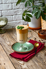 A glass of coffee with milk decorated with mint leaves on the table, dalgona coffee, vertical photo
