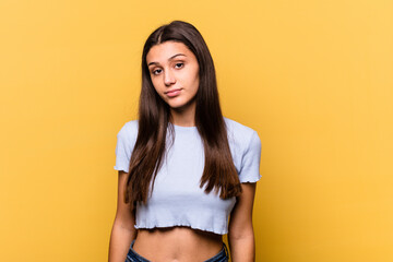 Young Indian woman isolated on yellow background sad, serious face, feeling miserable and...