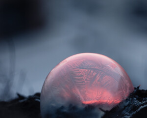 Frozen soap bubble with beautiful light and color on a wooden structure