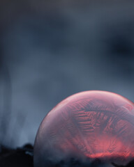 Frozen soap bubble with beautiful light and color on a wooden structure