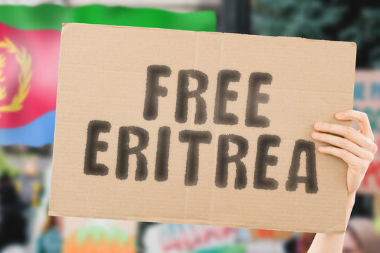The phrase " Free Eritrea " on a banner in men's hand with blurred Eritrean flag on the background. Protest. Riot. Violence. Economic crisis. Collapse. Politics. Streets. Save. Cruelty