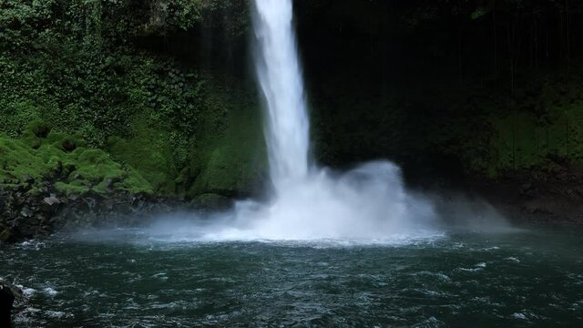 Powerful waterfall making lots of noise with water crashing into a natural pool Costa Rica la fortuna