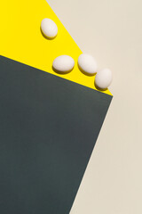 Minimalist easter composition with four eggs on yellow/ grey background.