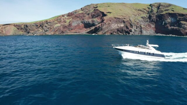 Speedboat travels on blue Atlantic Ocean with Ilh&eacute;u da Cevada in background