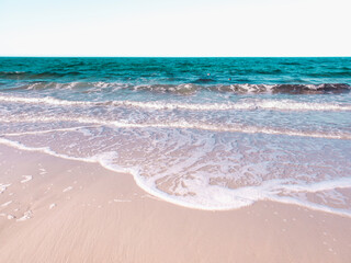 Calming Seascape with Turquoise Seawater, White Wave Lines, and Soft Pink Sand on the Beach