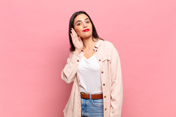 young pretty woman looking serious and curious, listening, trying to hear a secret conversation or...
